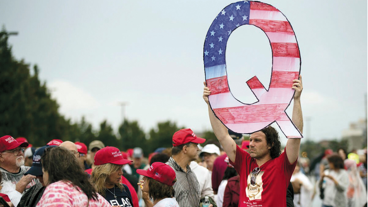 In this Aug. 2, 2018, photo, David Reinert holds a Q sign while waiting in line with others to enter a campaign rally with President Trump in Wilkes-Barre, Pa. — Matt Rourke/AP