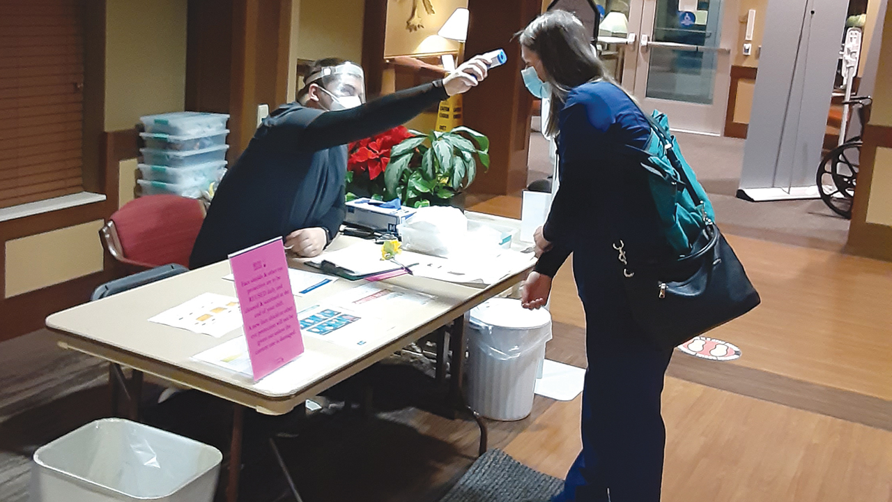 An Indiana National Guard serviceman checks for body temperature at the screening desk of the Greencroft Communities campus in Goshen. — Greencroft Communities