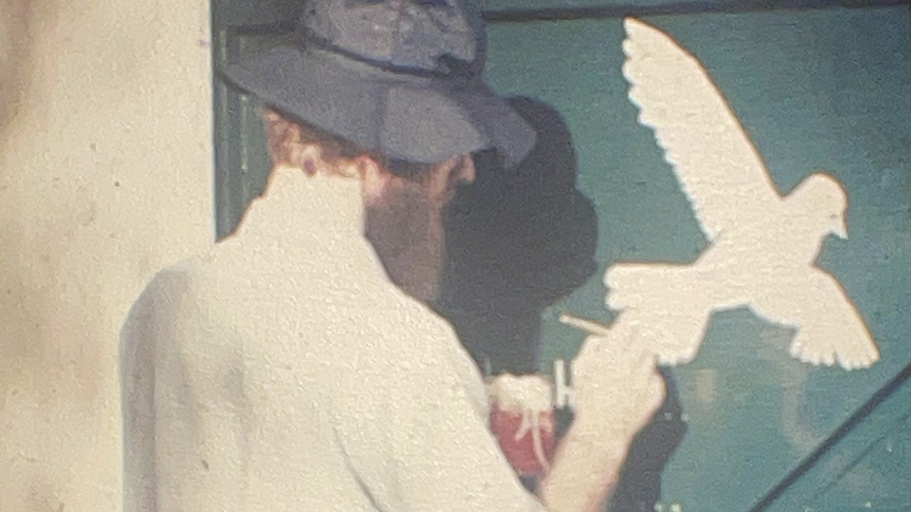 James Klassen paints a dove on the gate of the Mennonite center in Saigon as a symbol of peace after the war ended in 1975. — Courtesy of James Klassen