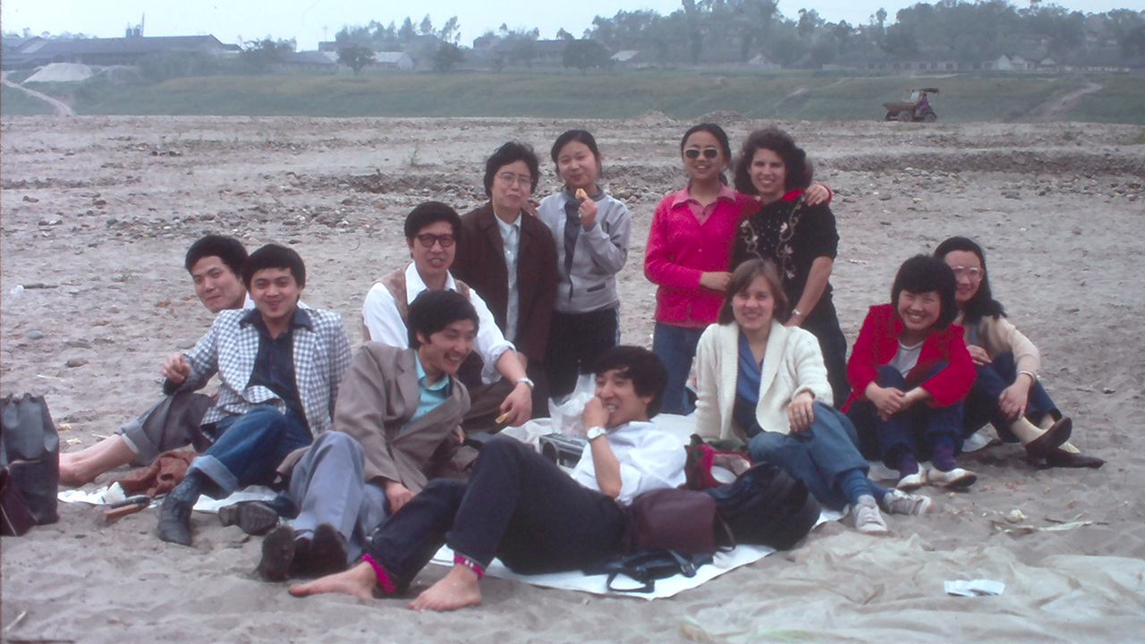 Mary Ann Zehr (back, far right) and Fran Martens Friesen picnic with students by the Tuo River in Luzhou, China, in 1986. — Courtesy of Mary Ann Zehr