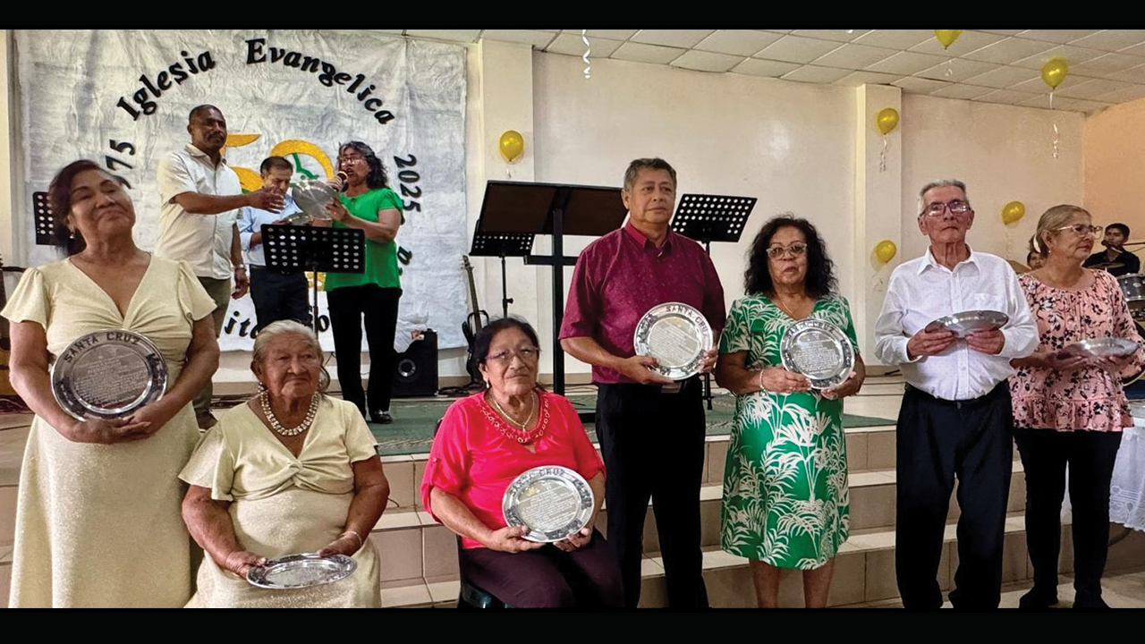 Francis Perez, Freddy Barrón and Ángela Opimí (in background) present commemorative plates to some of the founding families of the Bolivian Menno­nite Evangelical Church, represented by, from left, Severidad Jiménez, Amalia Jimenez, Maria Chuvé, Edgar Vaca, Beatriz Barrios, Roger Gutiérrez and Felicita Roca. — Tig Intagliata/MMN