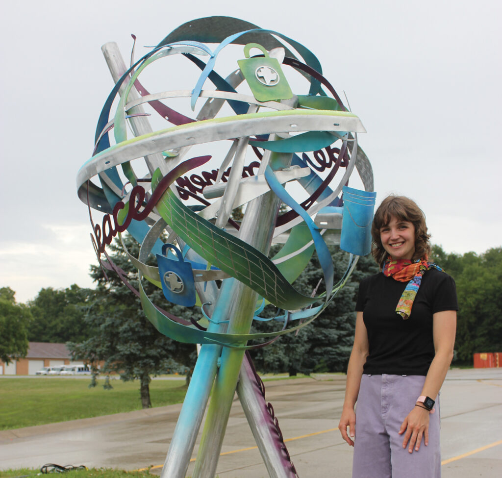 Artist Emma Zuercher with the sculpture in front of the Mennonite Central Committee building in Kidron, Ohio. — Jennifer Steiner/MCC