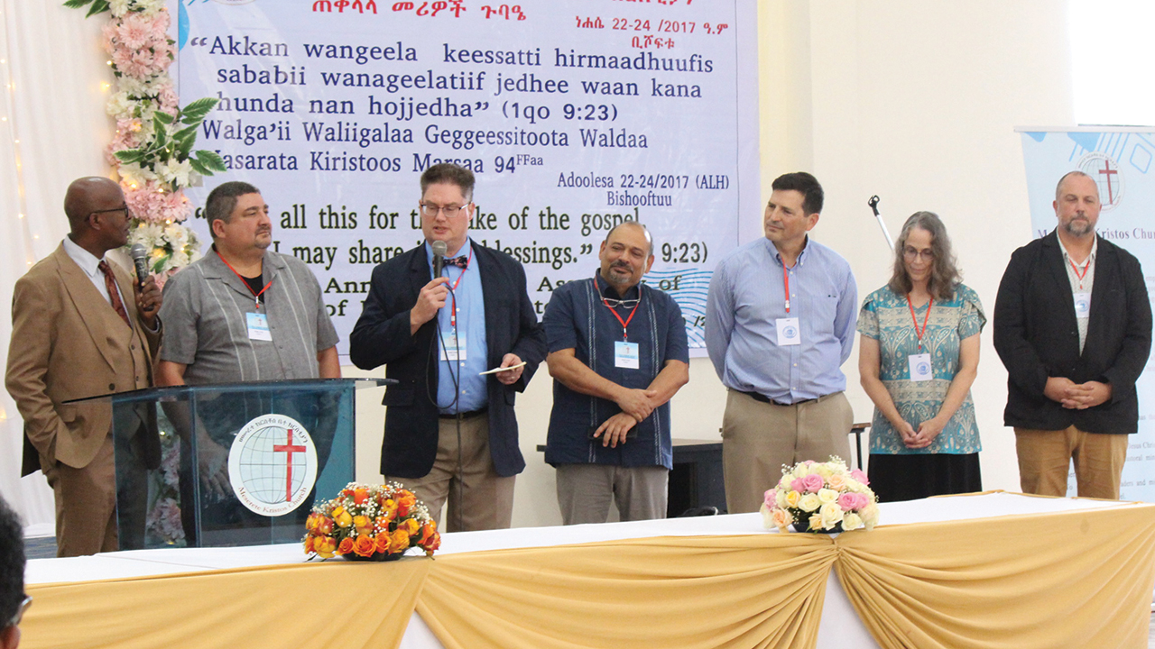 Meserete Kristos Church President Desalegn Abebe, left, is joined at the General Assembly by Evana Network executive director Matt Hamsher, Evana director of engagement Tyler Hartford, Eastern Mennonite Missions President Marvin Lorenzana, LMC global delegate and Groffdale Mennonite Church Pastor Tom Eshleman and wife Jennifer, and Rosedale Bible College academic dean Matthew Showalter. — MK Seminary Newsletter