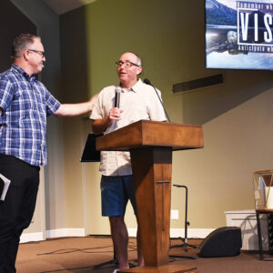 Clayton Paull, left, pastor of Hope Kingsburg, hands the microphone to Forrest Jenan, lead pastor of Neighborhood Church, at Hope Kingsburg’s final service. — Steve Wiest